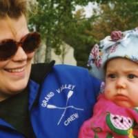 An GVSU crew alum smiles with a baby